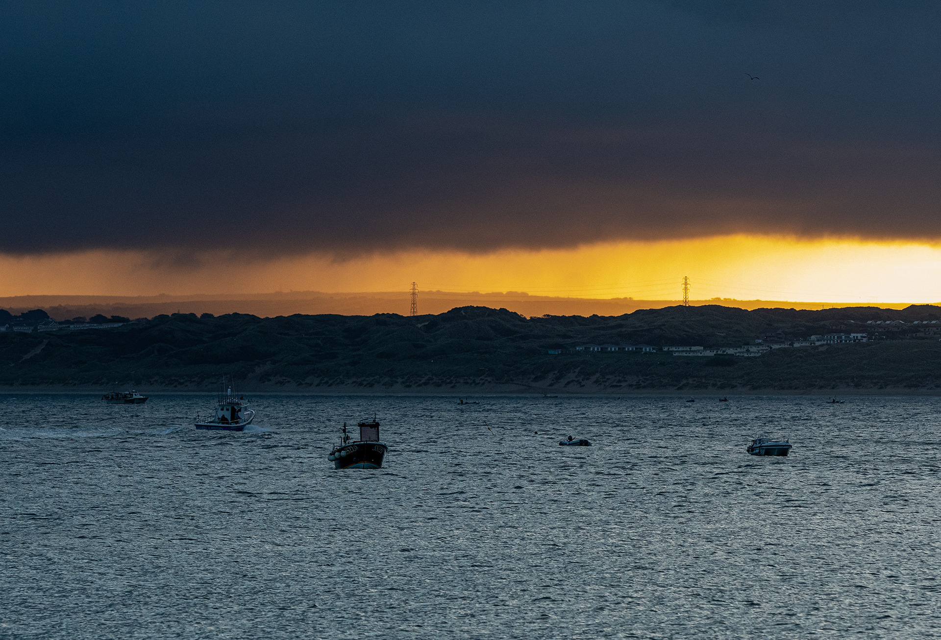 Rain clouds over boats in the sea.