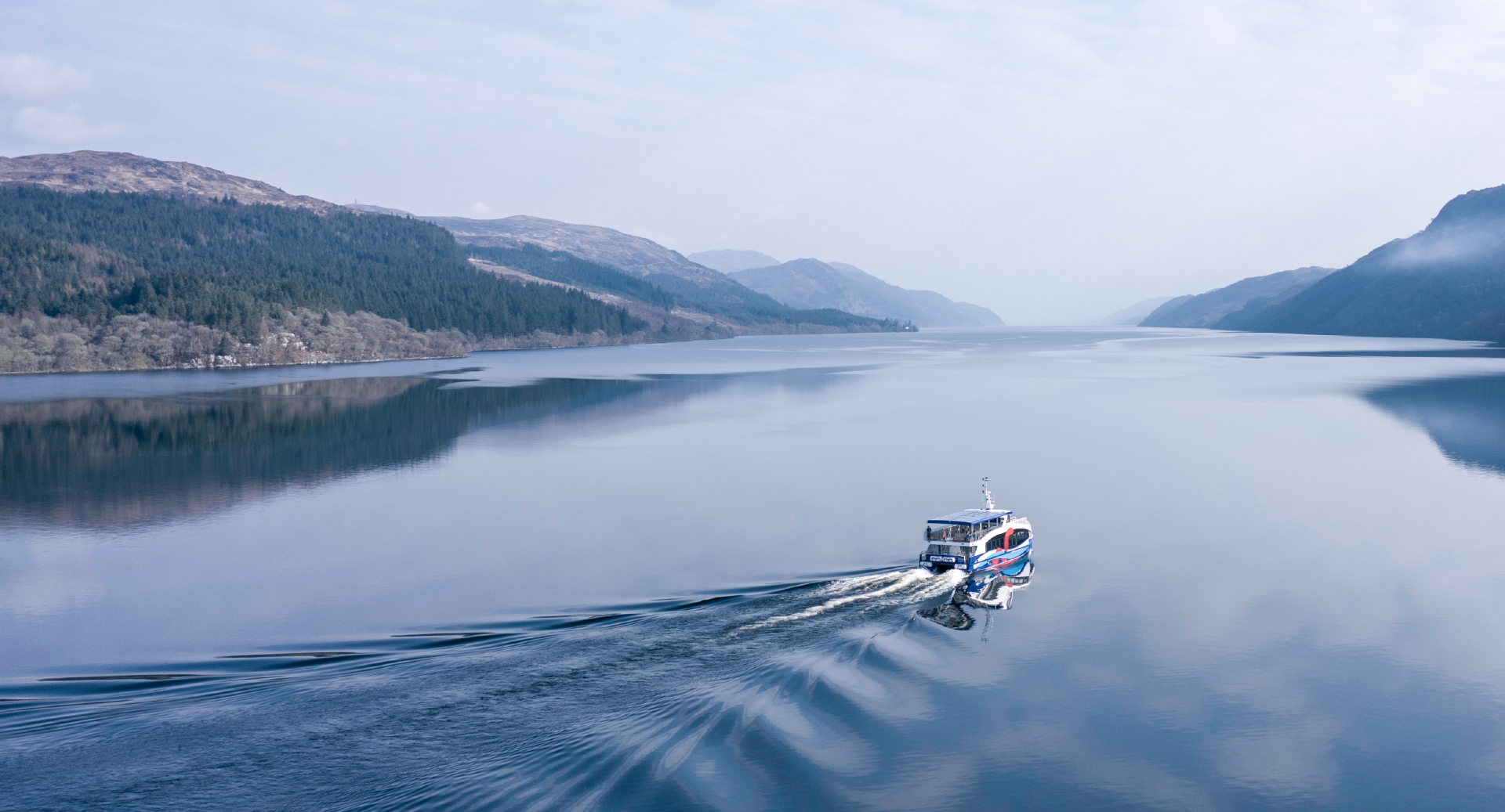 A boat on Loch Ness with mountains either side of the water.